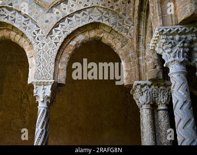 Arches et colonnes de style normand arabesques avec chapiteaux sculptés de style roman à l'extérieur du cloître bénédictin de Monreale en Sicile Banque D'Images