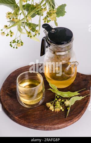 Théière en verre avec thé de linden filtre et verre transparent sur fond blanc. Vue de dessus. Banque D'Images