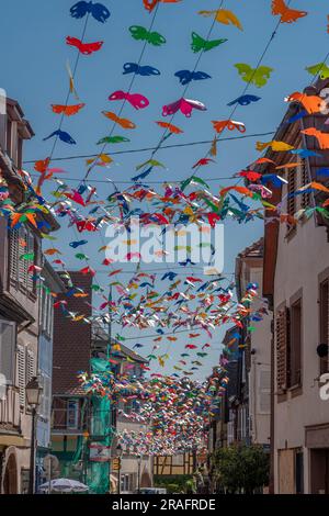 Barr, France - 06 24 2023 : ville de Barr. Vue sur une décoration aérienne de papillons colorés avec des maisons alsaciennes typiques et un fond bleu ciel Banque D'Images