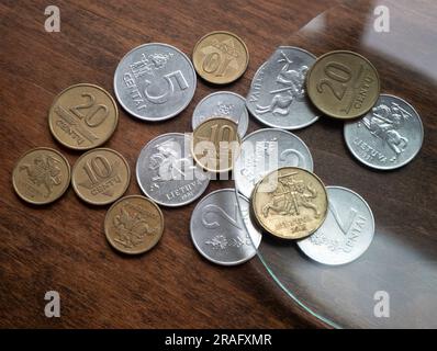 Ancienne monnaie métallique lituanienne sous la loupe sur la table en bois, mise au point sélective. Devises locales Banque D'Images