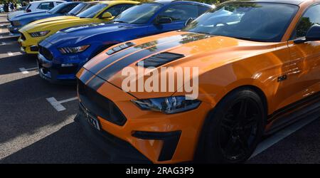Trois Ford Mustang voitures garées dans une rangée de jaune orange et bleu Banque D'Images