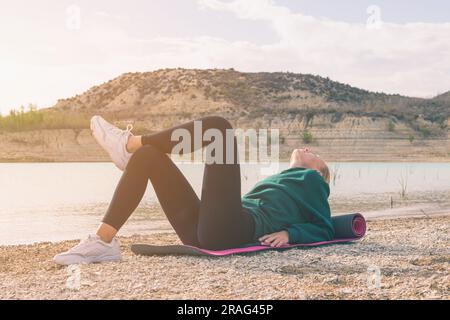 randonneur féminin réussi apprécie la vue sur le sommet de la montagne méditant couché sur tapis de yoga, beau paysage de la nature avec femme. Photo de haute qualité Banque D'Images