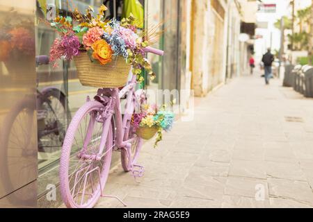 vélo de recteur de couleur rose se dresse près de la vitrine décorée de fleurs. Photo de haute qualité Banque D'Images