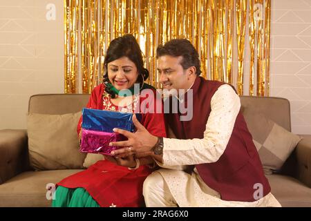 Heureux homme indien apporte beau cadeau pour sa femme dans Saree. Tous deux portent des vêtements ethniques indiens sur Diwali et célèbrent le festival. Banque D'Images