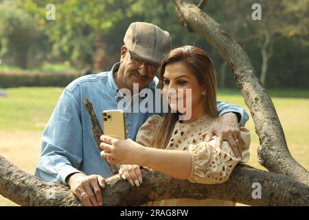 Couple indien âgé ayant un bon moment romantique dans le parc verdoyant. Ils apprécient, sourient et ont des moments joyeux. Banque D'Images