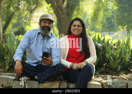 Couple indien âgé ayant un bon moment romantique dans le parc verdoyant. Ils apprécient, sourient et ont des moments joyeux. Banque D'Images