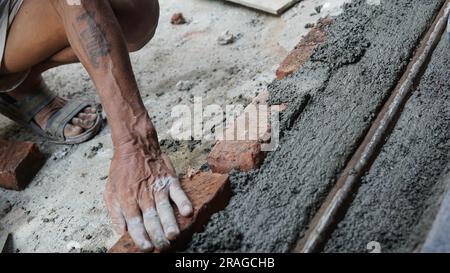 Main de travail ou de maçon posant des briques de près. Bricklayer travaille à la rangée de briques. Travaux de briques sur le chantier de construction Banque D'Images