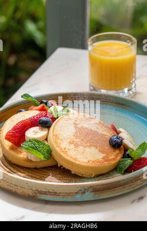 crêpes moelleuses avec des fruits sur un matin ensoleillé Banque D'Images