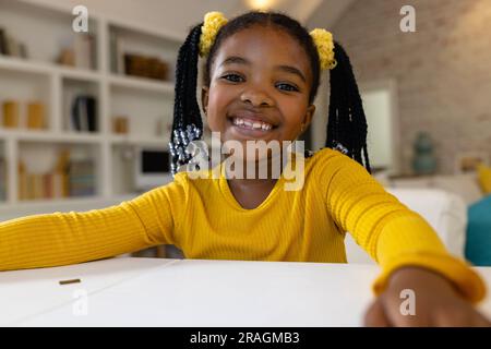 Heureuse fille afro-américaine faisant appel vidéo à la maison Banque D'Images