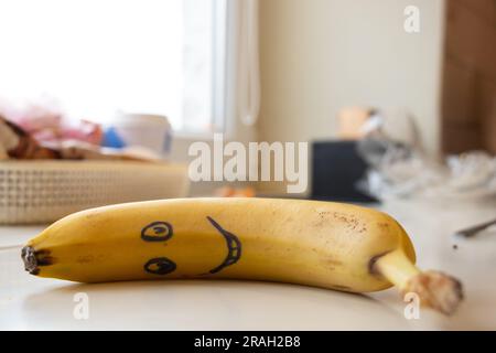 un sourire est tiré sur une banane qui se trouve sur la table le matin pour le petit déjeuner pour un enfant Banque D'Images