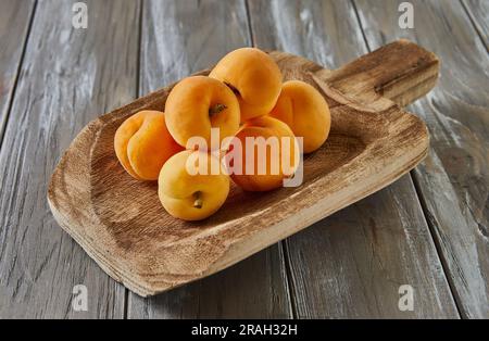 Abricots frais reposent sur la louche en bois sur fond en bois gris Banque D'Images