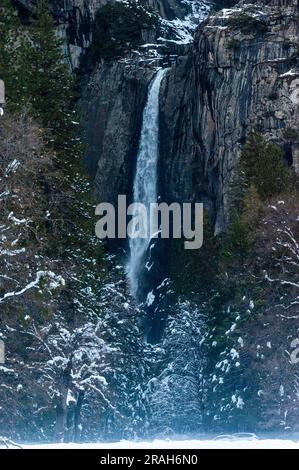 Une photo au téléobjectif du yosemite tombe un après-midi d'hiver avec des arbres enneigés au premier plan. Banque D'Images