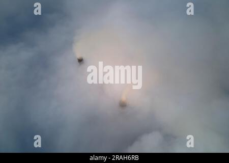 Les tuyaux hauts de la centrale au charbon émettant de la fumée noire toxique se déplaçant vers le haut sur un brouillard blanc polluant l'air. Production d'énergie électrique avec fossile Banque D'Images