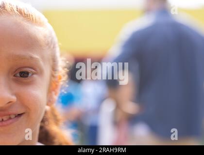 Portrait à moitié face d'une jeune fille de l'école élémentaire biracial souriante dans le terrain de jeux de l'école, espace de copie. Éducation, inclusion, école primaire et apprentissage Banque D'Images