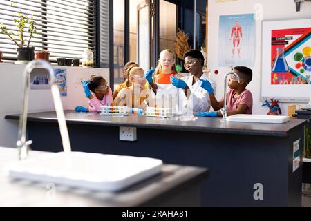 Diverses enseignantes et écoliers faisant une expérience en classe de chimie. Éducation, école primaire et concept d'apprentissage. Banque D'Images