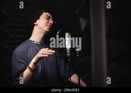 l'homme chante dans le microphone, le studio d'enregistrement professionnel, les écouteurs. Murs mous noirs, isolation phonique. singer enregistre sa chanson. rap Banque D'Images