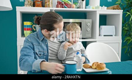 Le père et le fils sont assis sur une table pour prendre le petit déjeuner dans la salle à manger Banque D'Images