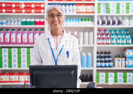 Femme d'âge moyen avec tatouages travaillant à la pharmacie avec un sourire heureux et frais sur le visage. personne chanceux. Banque D'Images