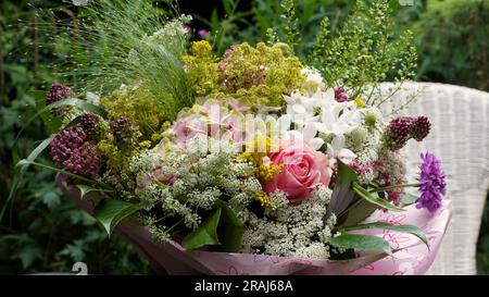 Un bouquet de belles fleurs d'été. Couleurs pastel. Une chaise en osier blanc dans le fond. Banque D'Images