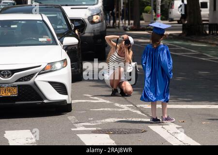 Une jeune fille en casquette bleue et en robe est photographiée sur la Cinquième Avenue à New York, juin 2023. Ce peut être mère et fille. Banque D'Images