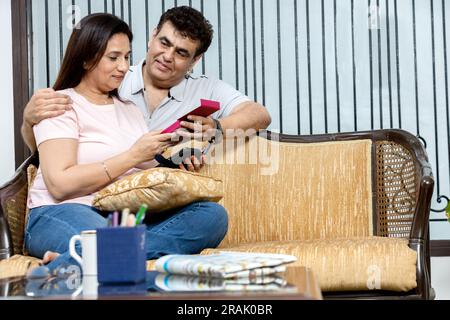 Mari indien couvrant les yeux de sa femme, faisant la surprise d'anniversaire, donnant son cadeau à la maison. Couple millénial diversifié célébrant le b-day ensemble, enjoyi Banque D'Images