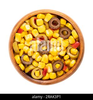 Dans un bol en bois, mélanger le maïs en conserve, les olives vertes et noires tranchées et les dés de poivron rouge. Mélange de maïs méditerranéen prêt-à-manger, en accompagnement. Banque D'Images