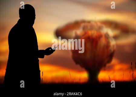 Le concept d'une frappe nucléaire. Silhouette d'un homme avec une télécommande dans ses mains faisant une explosion. Un homme politique qui a lancé une guerre nucléaire Banque D'Images