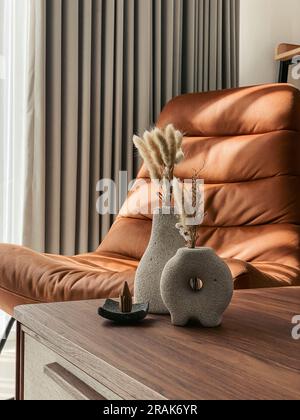 Vases décoratifs en pierre de lave avec fleurs sèches et cônes d'encens sur la table dans la salle de séjour à proximité Banque D'Images