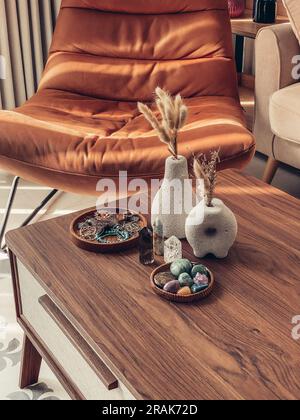 Vases décoratifs en pierre de lave avec fleurs sèches et cristaux de guérison sur la table dans la salle de séjour à proximité Banque D'Images