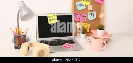 Ordinateur portable avec notes adhésives, écouteurs, café et papeterie sur le lieu de travail Banque D'Images