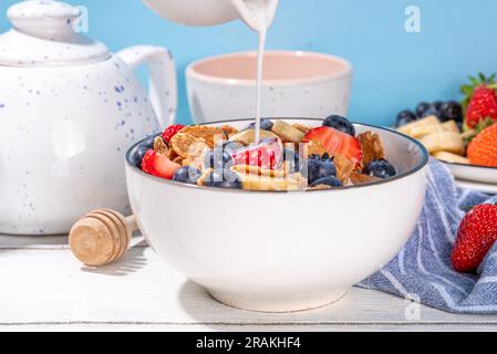 Petit déjeuner d'été diététique vitaminique sain. Céréales flocons multigrains avec yaourt ou lait et fraises, myrtilles, sur l'espace de copie de table de cuisine Banque D'Images