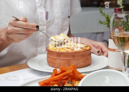 Femme mangeant moussaka grecque traditionnelle préparée dans un pot d'argile Banque D'Images