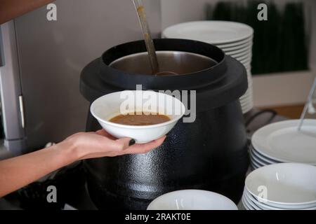 Femme prenant de la soupe d'une file d'attente de buffet Banque D'Images