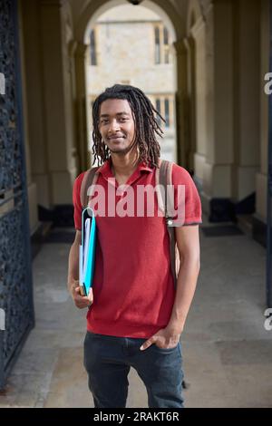 Portrait d'un étudiant portant des dossiers à l'extérieur du bâtiment de l'université d'Oxford, au Royaume-Uni Banque D'Images