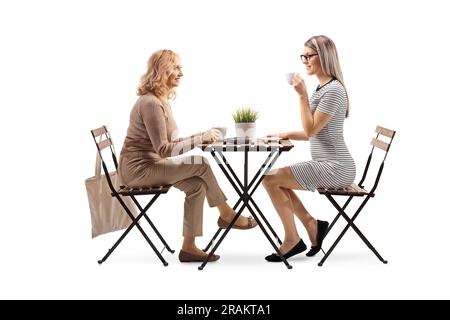 Femme mature et plus jeune assise à une table et buvant du café isolé sur fond blanc Banque D'Images