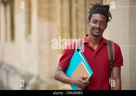 Portrait d'un étudiant portant des dossiers à l'extérieur du bâtiment de l'université d'Oxford, au Royaume-Uni Banque D'Images