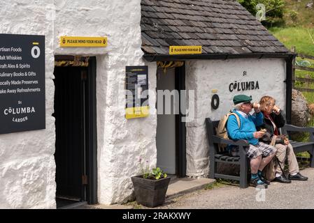 Île d'Iona, Écosse, Royaume-Uni. 6 juin 2023. Les touristes s'arrêtent pour déjeuner assis sur un banc en bois devant un garde-manger vendant de la nourriture et des boissons sur la petite île Banque D'Images