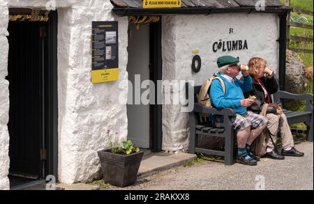 Île d'Iona, Écosse, Royaume-Uni. 6 juin 2023. Les touristes s'arrêtent pour déjeuner assis sur un banc en bois devant un garde-manger vendant de la nourriture et des boissons sur la petite île Banque D'Images