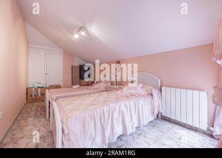 Chambre avec lits jumeaux, armoire encastrée avec portes blanches et plafonds inclinés Banque D'Images
