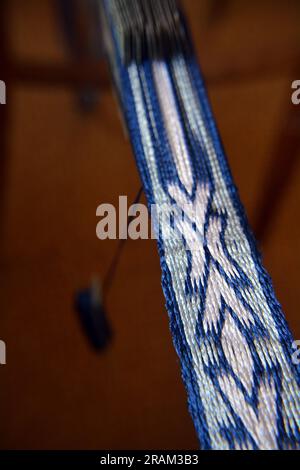 Gros plan d'une ceinture de soie blanche et bleue fabriquée à la main par tissage de tablettes. Image verticale avec mise au point sélective Banque D'Images