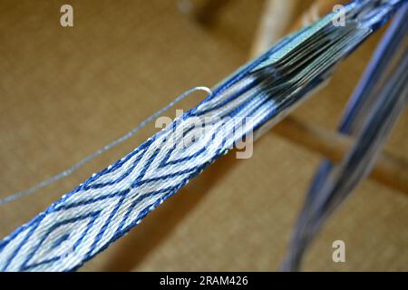 Gros plan d'une ceinture de soie blanche et bleue fabriquée à la main par tissage de tablettes. Image horizontale avec mise au point sélective Banque D'Images
