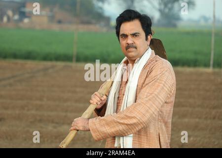 Portrait d'un fermier indien heureux labourant le champ manuellement en une journée. Tenir un outil agricole en main. Pelle et houe à outils de creusement en main. Banque D'Images