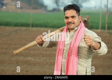 Portrait d'un fermier indien heureux labourant le champ manuellement en une journée. Tenir un outil agricole en main. Pelle et houe à outils de creusement en main. Banque D'Images