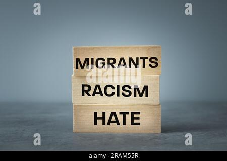 Le problème du racisme et de la haine migrants, écrit sur des blocs de bois migrants racisme haine, triste fond gris, copie espace, concept lié aux immigrants Banque D'Images