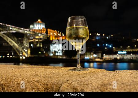 Boire du vin de Porto blanc dans un restaurant à Porto à côté de la rivière dans la soirée avec belle vue. Banque D'Images