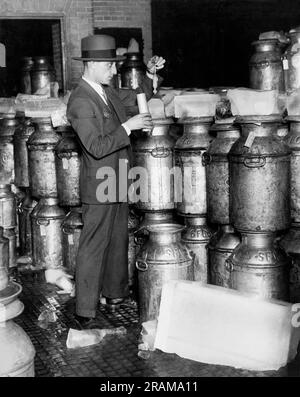 New York, New York : c. 1926 Un inspecteur du ministère de la Santé de la ville de New York prend une lecture de lactomètre sur la plate-forme de distribution d'une usine de pasteurisation. Il mesure la gravité spécifique et donc la richesse du lait. Banque D'Images