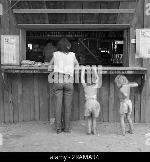 Subventions Pass, Oregon : août 1939 Un préparateur de sauts avec ses deux enfants va de la fenêtre du payeur au magasin de l'entreprise qui l'y jouxte. Elle avait gagné quarante-deux cents ce matin, et l'avait dépensé pour une livre de saucisse de bologne, un paquet de cigarettes 'sensation' et un gâteau de l'autre. Banque D'Images