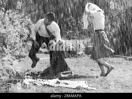 Hollywood, Californie: 9 septembre 1965 ce couple de films a eu un délicieux déjeuner pique-nique jusqu'à ce que l'homme des effets spéciaux soit venu le long et les a bénis avec un déversant torrentiel. Banque D'Images