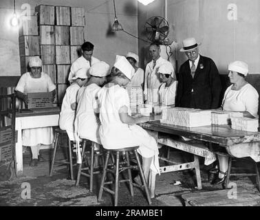 New York, New York : c. 1926 Un inspecteur du département de la santé de la ville de New York qui supervise l'emballage du beurre dans une usine d'emballage. Banque D'Images