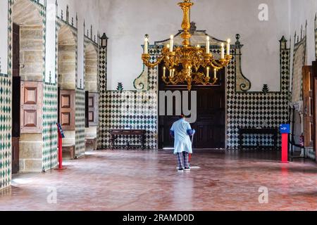 Une femme de ménage dépoussière le sol au Swan Hall ou au Great Hall avec des panneaux de plafond décorés peints avec des cygnes couronnés au Palais national de Sintra, au Portugal. Les palais architecturaux et de conte de fées Romanticistes attirent des touristes du monde entier. Banque D'Images